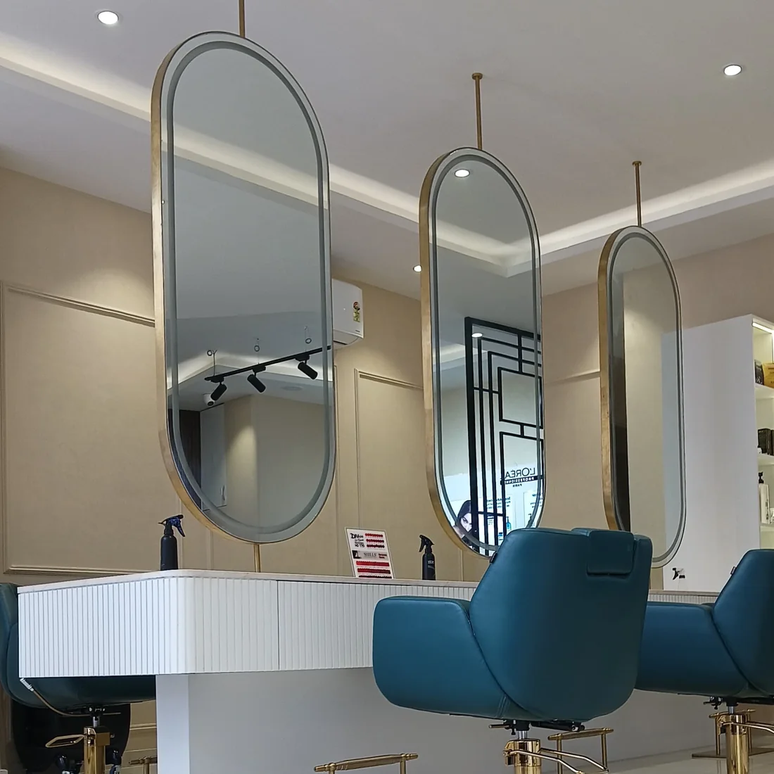 Styling stations with brass oval mirrors and teal chairs