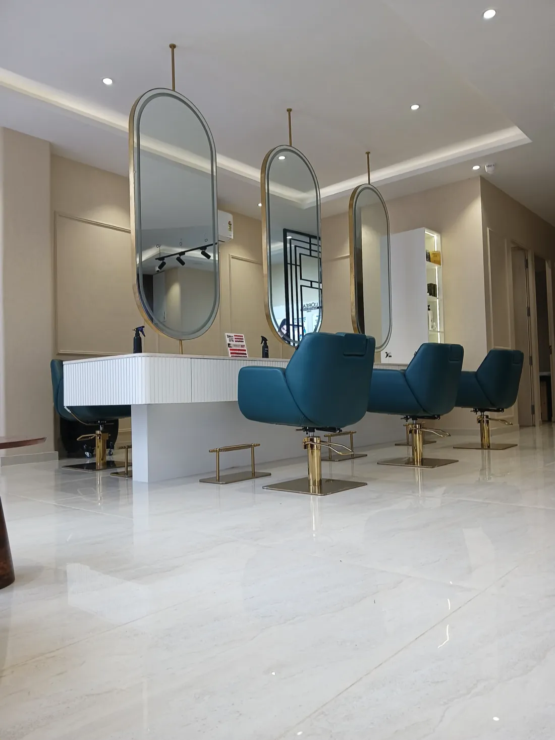 Styling stations at MONSOON PRO SALON, with brass oval mirrors and teal leather chairs
