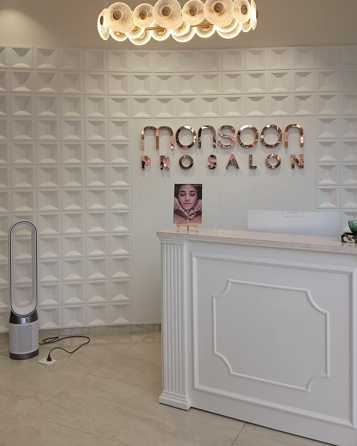 The reception desk at MONSOON PRO SALON, below the rose gold salon sign